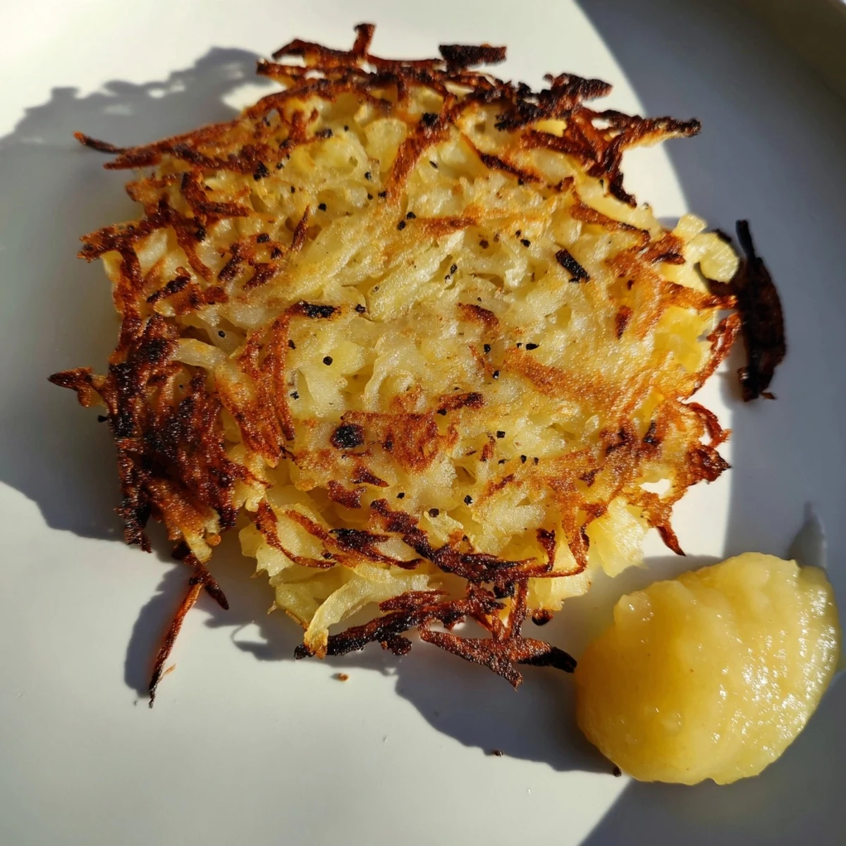 Golden-brown German potato pancakes sit ready to eat, served with a dollop of fresh sour cream.