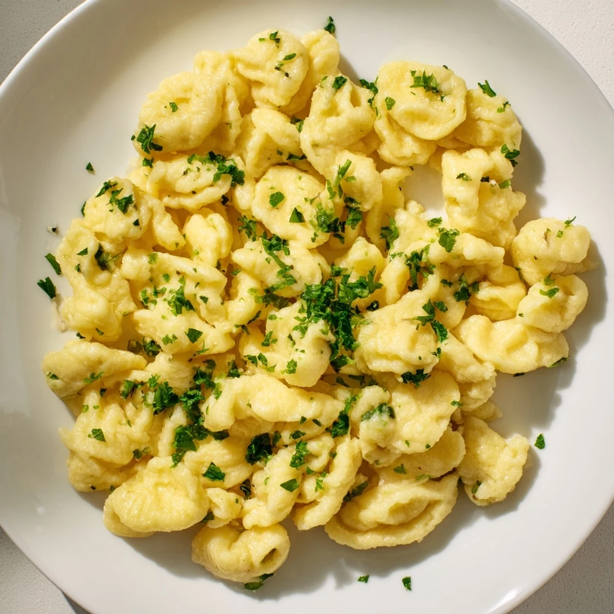 Golden-brown spaetzle, pillowy German noodles bathed in melted butter and fresh parsley.