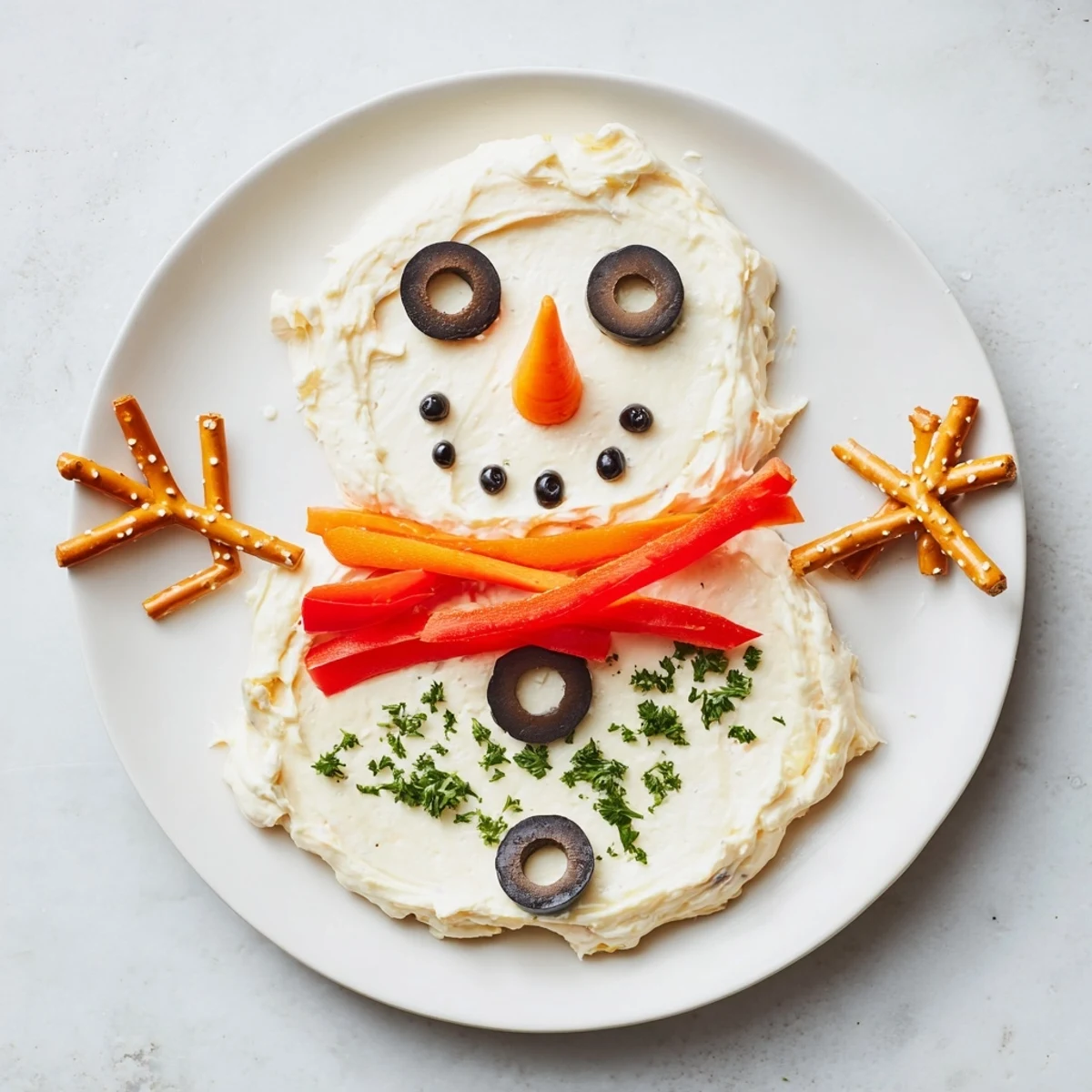Melting snowman dip, a creamy winter appetizer decorated with olives, carrot, and pepper.