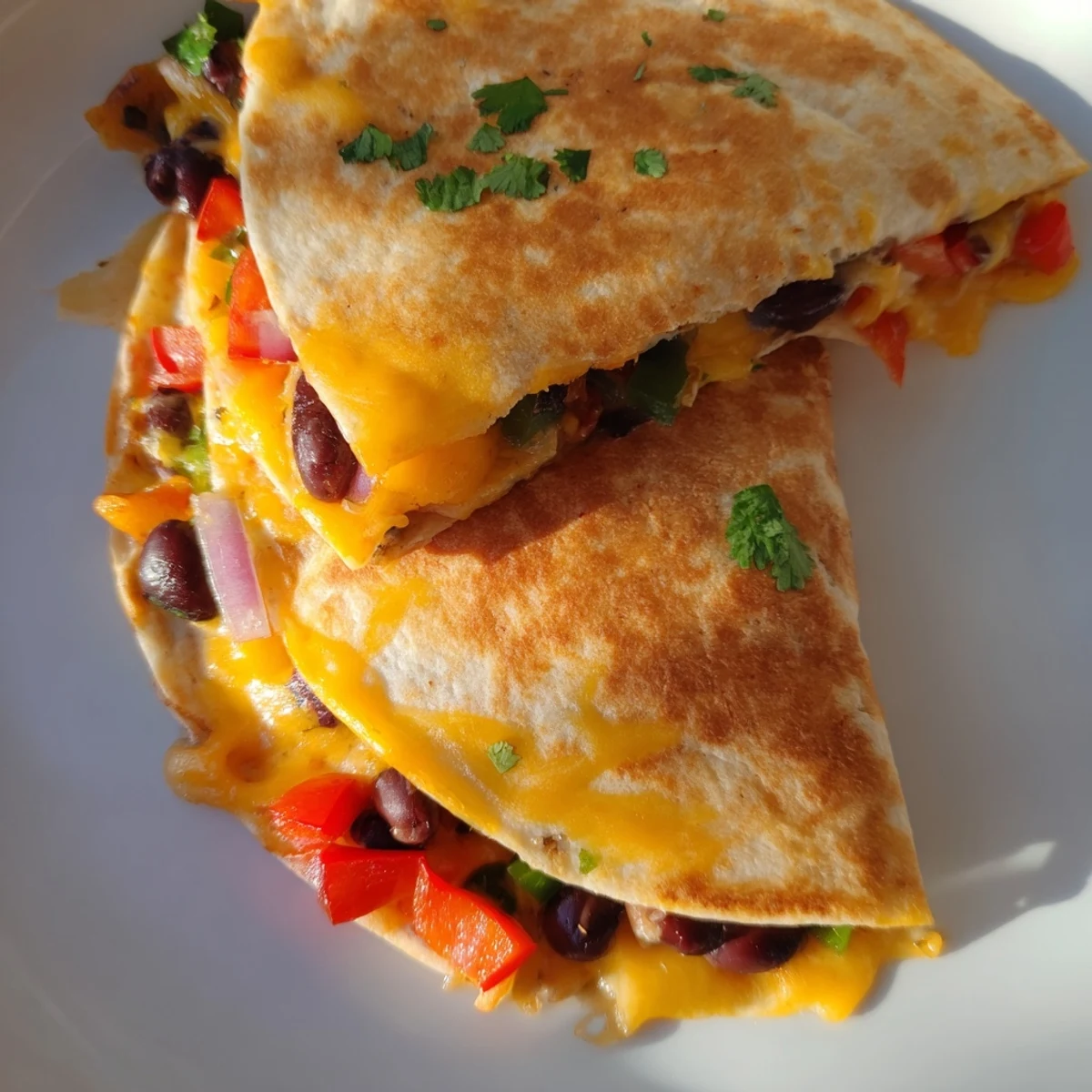 Warm, cheesy black bean quesadilla sliced and ready to serve with fresh cilantro and salsa.