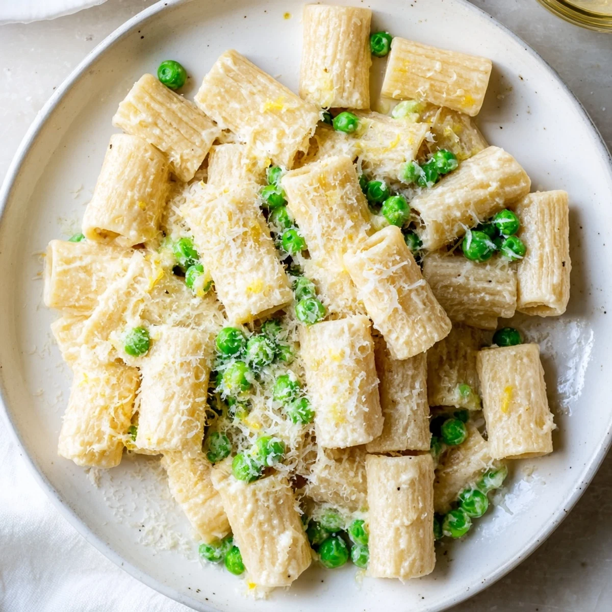 Rigatoni mit Erbsen und Zitronen-Ricotta wird frisch und cremig auf einem Teller angerichtet.