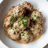 A close-up of delicious Swedish Meatballs with mashed potatoes and bright red lingonberry jam.