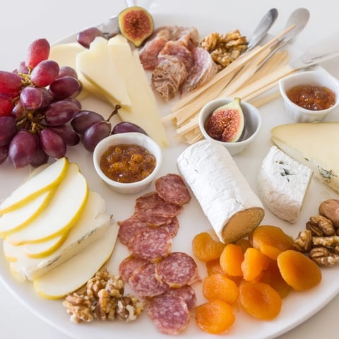 An overflowing charcuterie board with cheeses, perfect for a 2026 Wine Pairing Board.
