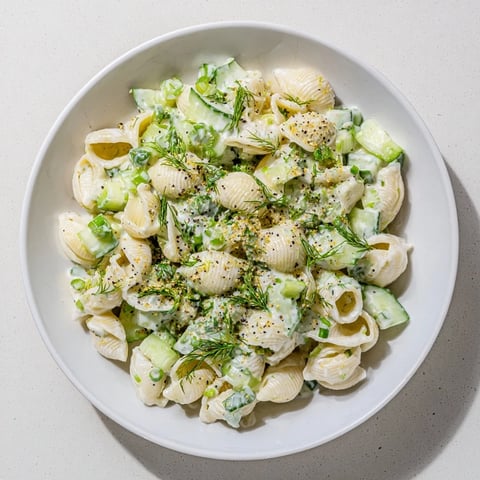 Cucumber Crunch Pasta Salad mit kleinen Muschelnudeln, krossen Gurkenwürfeln und cremigem Dressing auf einer blauen Schale.