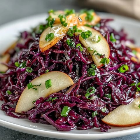 Red Cabbage Coleslaw With Apple and Parmesan salad topped with shaved cheese and fresh parsley on a plate.