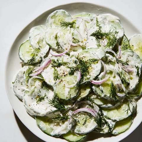 Close-up of Omas German Cucumber Salad, highlighting the crisp cucumbers and tangy dressing.
