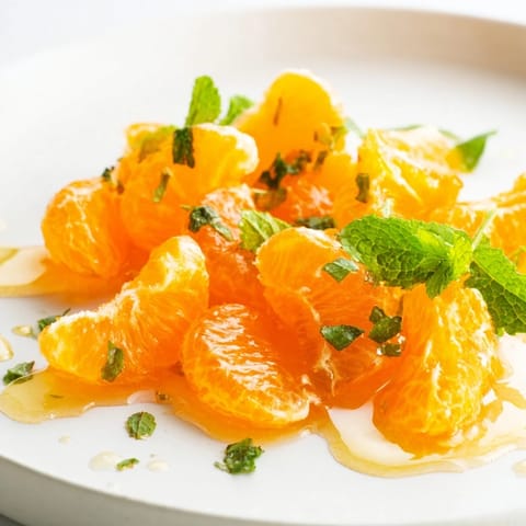 Close-up of a refreshing clementine and mint winter fruit salad, showcasing citrus and green leaves.