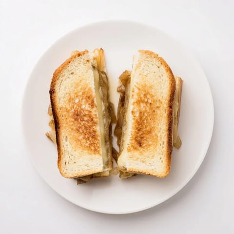Golden-brown grilled sandwich slices with melted Gruyère cheese and sweet caramelized onions peeking out of crispy country bread.