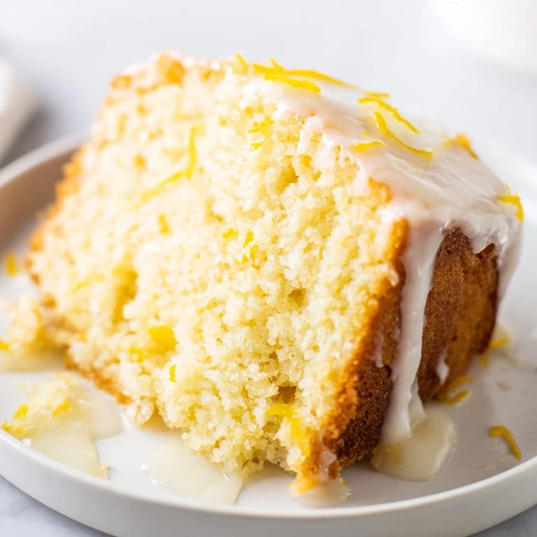 Moist slice of Lemon Yogurt Cake, drizzled with glaze, ready to be enjoyed with tea.