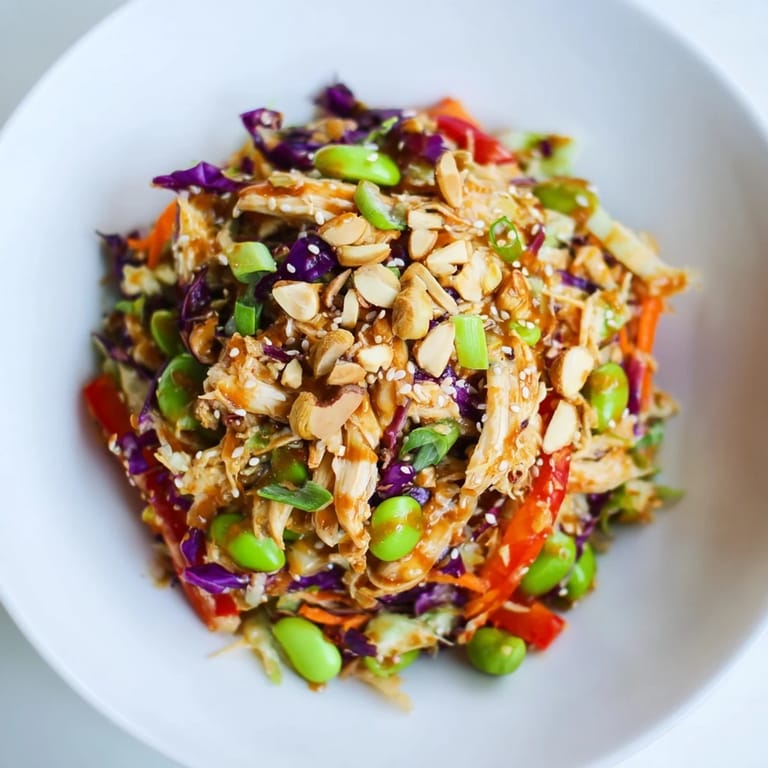 Gesunder Edamame Crunch Hähnchensalat mit glasierten Nüssen und leuchtenden Karottenstreifen auf dem Teller.  